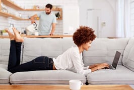 Woman laying on a couch working on her laptop