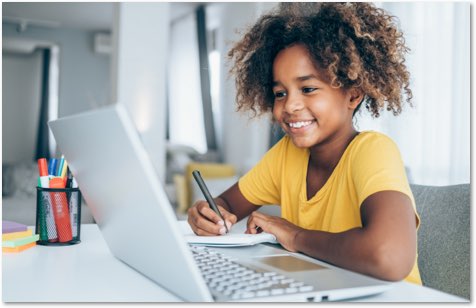 Young black child taking notes while watching something on a laptop