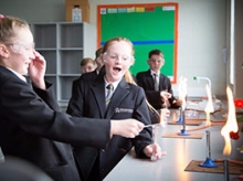 Children in school uniforms looking excited about a science experiment