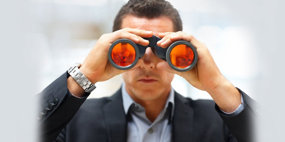 Man in a suit looking through binoculars with orange lenses