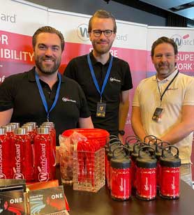 3 WatchGuardians at a tradeshow behind a table full of WatchGuard give aways