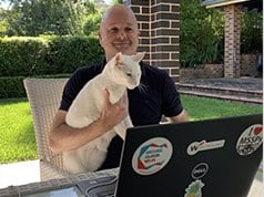Un dipendente di WatchGuard che lavora dal suo cortile con un gatto bianco in braccio