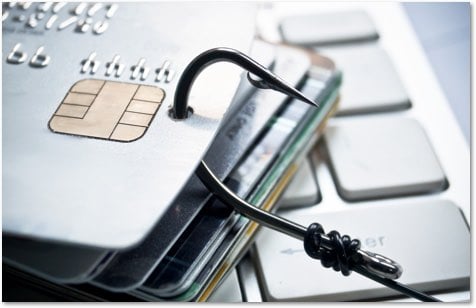 stack of credit cards on a keyboard with a fishhook through the top one