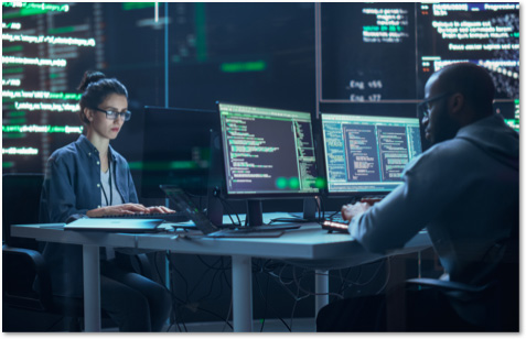 Woman and man working across from each other at desks in a SOC