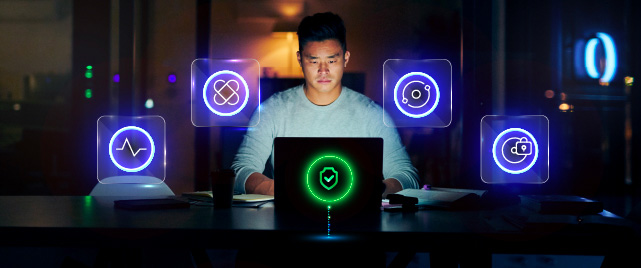 Man in a dark room lit by his laptop screen with glowing icons around him