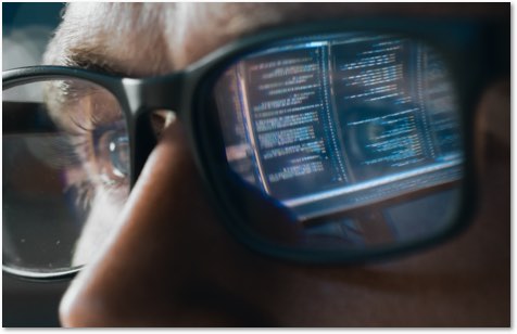 Close up of a man's face with code reflecting in his glasses