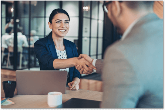 Smiling woman shaking hands with a man in an office setting