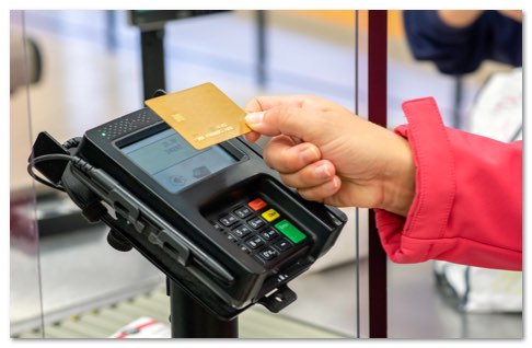 hand holding a bank card over a payment terminal
