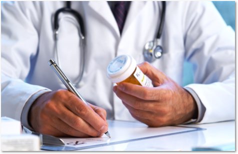 Doctor writing a prescription while holding a pill bottle