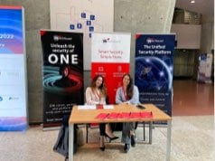 2 WatchGuard women sitting at a tradeshow table in front of marketing banners