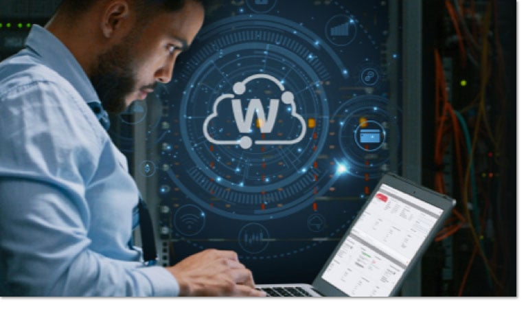 Black man working on a laptop with a WatchGuard Cloud icon in the window behind his desk