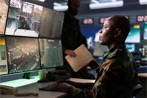 black man watching network activity on several monitors