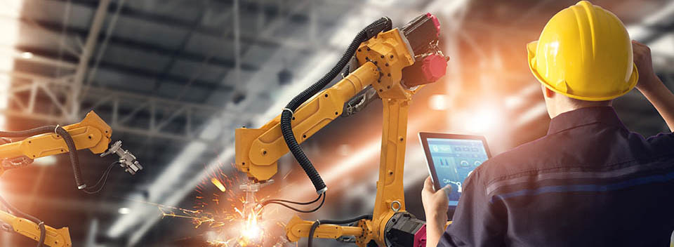 Worker in a yellow hardhat controlling machinery with a tablet computer