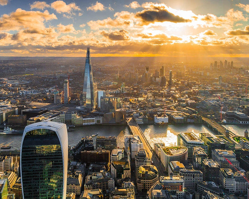 sun shining through fluffy clouds over London cityscape