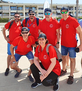 Eine Gruppe WatchGuardians, die mit roten Shirts, Sonnenbrillen und Baseballmützen posiert