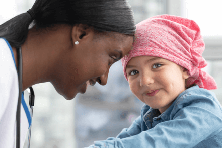 CSR - Lächelnde Ärztin mit einem Kind mit rosa Kopftuch