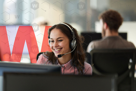 Frau mit Headset arbeitet an einer Reihe von Computern