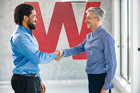 Zwei lächelnde Menschen, die sich die Hände schütteln.