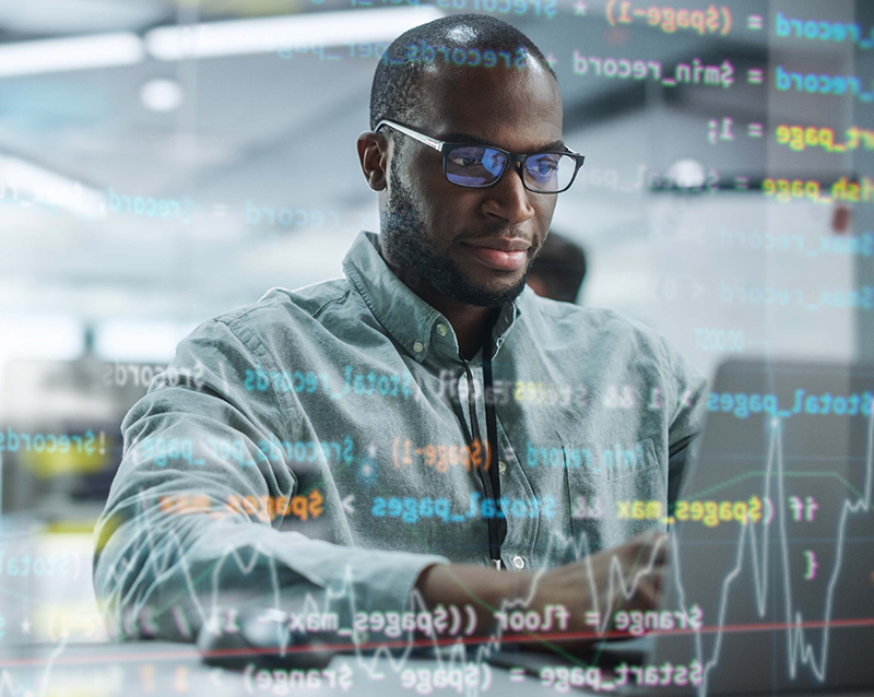 black man in glasses working at a laptop with screen data superimposed over his figure