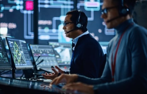 Two men in headsets working at a SOC