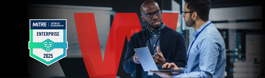 Two businessmen talking with an open laptop next to a MITRE badge