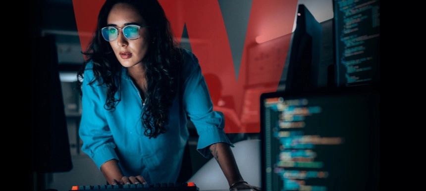 Woman in glasses and a blue shirt looking at monitors