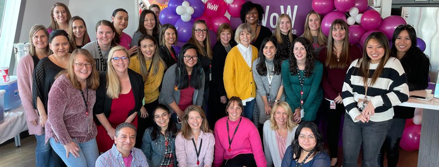 Groupe de plusieurs femmes réunies devant la bannière Women of WatchGuard