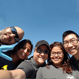 5 empleados de WatchGuard mirando hacia la cámara, con un cielo azul a sus espaldas