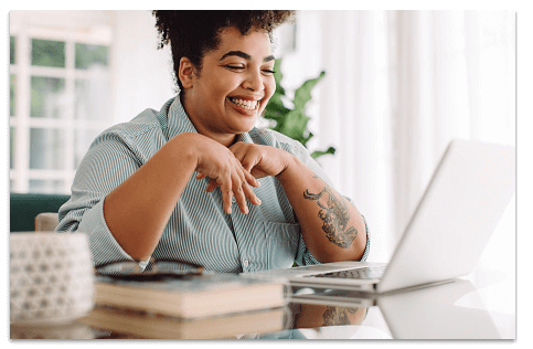 Smiling woman looking at a laptop screen in an airy white room