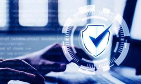 Checkmark in a shield in front of a computer user