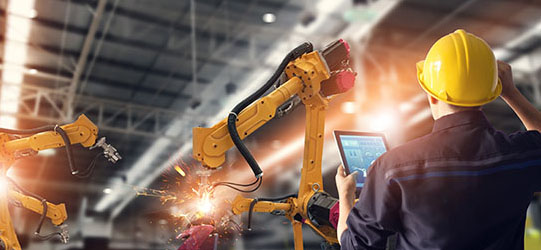 Person in gelbem Schutzhelm in einer Werkshalle