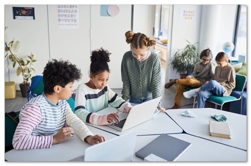 Tweens working together on a laptop in an open classroom setting