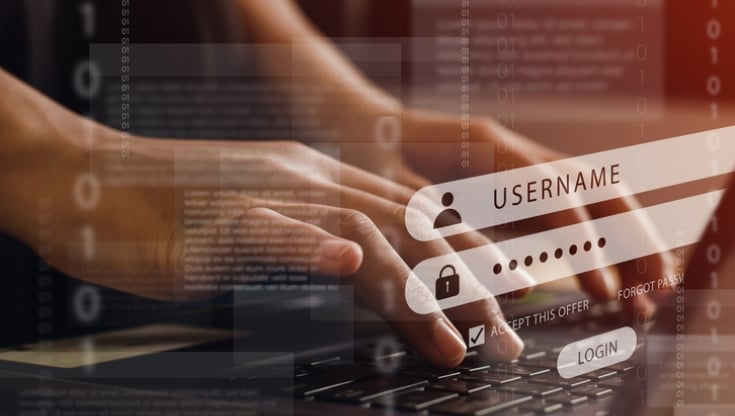 Hands typing on a laptop keyboard with digital login screen overlay showing username and password fields, symbolizing cybersecurity and account protection.