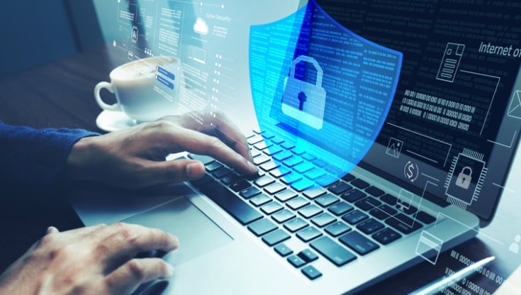 Person typing on a laptop with a transparent digital shield and lock icon overlay, representing cybersecurity, data protection, and secure online access.