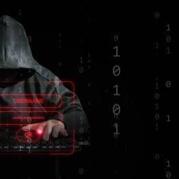 Hooded hacker at keyboard attempting brute-force login attack, with red digital lock and username/password fields overlaid on binary code background.