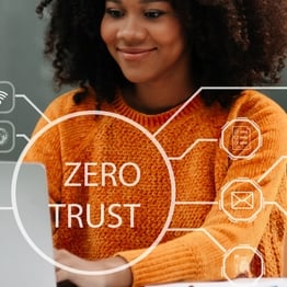 A professional woman works on her laptop in a modern office, with a digital overlay reading “Zero Trust.” The image represents secure, identity-based remote access and the shift from traditional VPNs to Zero Trust Network Access.