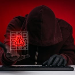 Hooded cybercriminal holding a glowing QR code with a warning symbol, representing QR code phishing, social engineering, and cryptocurrency cyber threats.