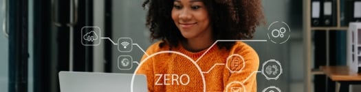 A professional woman works on her laptop in a modern office, with a digital overlay reading “Zero Trust.” The image represents secure, identity-based remote access and the shift from traditional VPNs to Zero Trust Network Access.