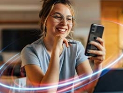 Blond woman in glasses smiling and looking at her phone