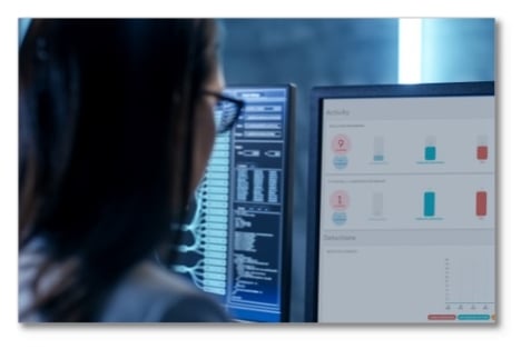 Woman in glasses working on a monitor showing reports