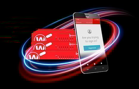 Phone showing an AuthPoint verification screen in front of a stack of red WatchGuard Fireboxes