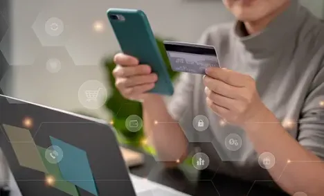 person holding their credit card next to their mobile phone