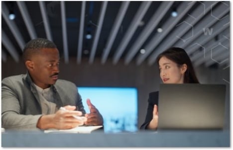 Two people sitting in a conference space discussing something
