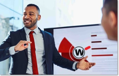 Man in a dark suit and red tie in front of a chart with a WatchGuard icon next to it