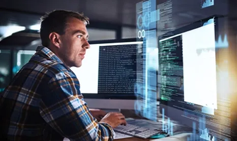 Man working on code across two monitors