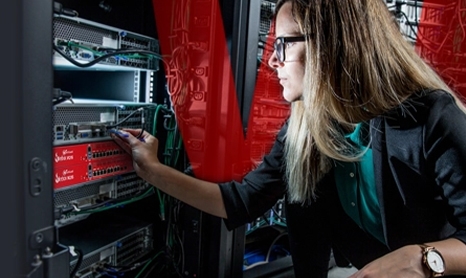 blonde woman adjusting a red WatchGuard Firebox in a server rack