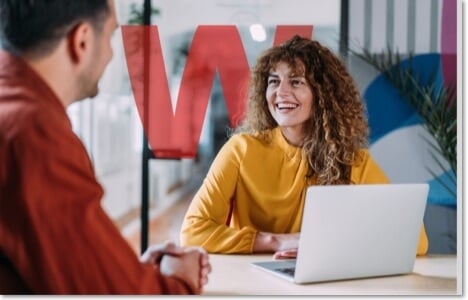 Co-workers smiling at each other with a laptop between them