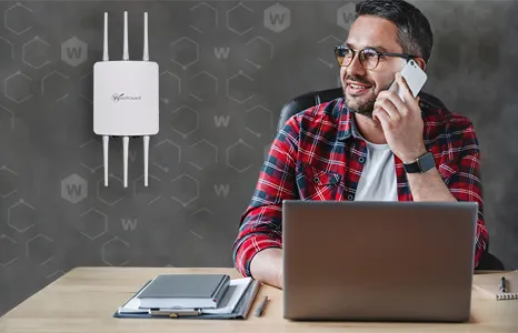 man on the phone in front of his laptop with a WatchGuard access portal on the wall