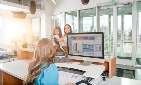 mother and child speaking to a nurse at a reception desk