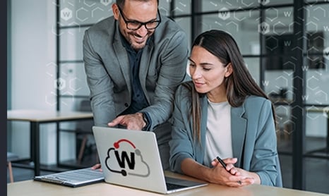 Man leaning over a woman pointing at something on her laptop screen